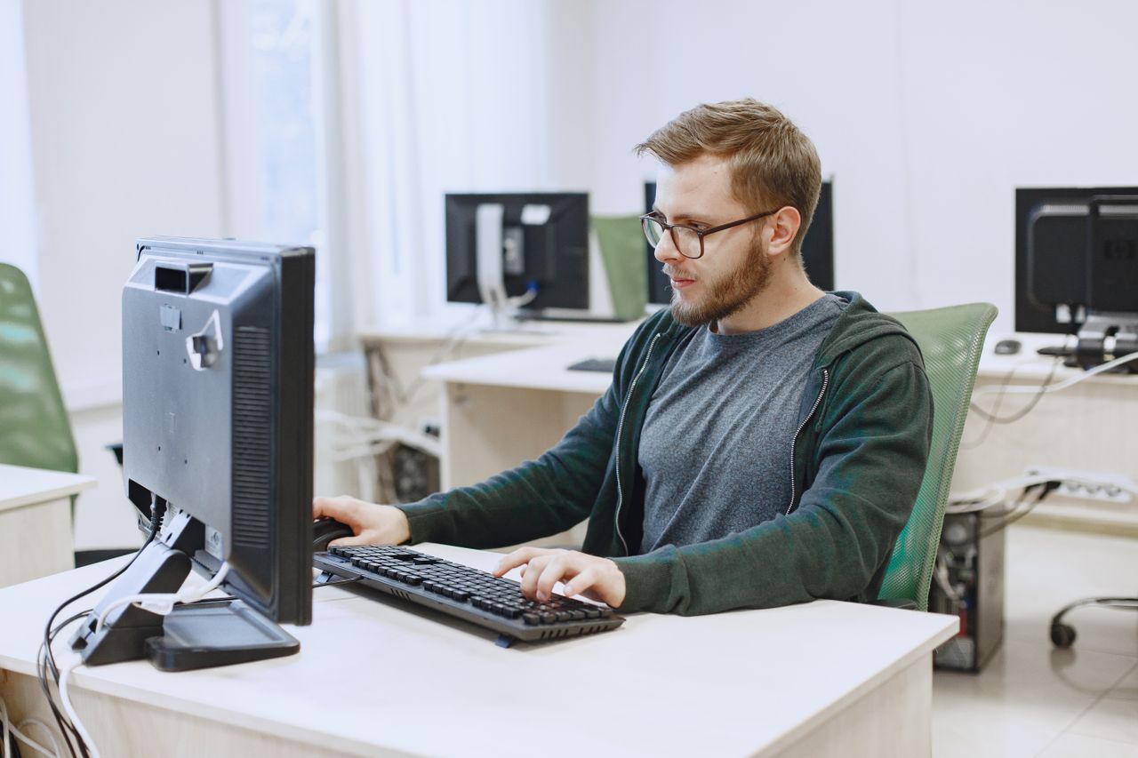 Mastering the First Impression: Your intriguing post title goes here Young man with eyeglasses working on a desktop computer in a modern office environment.