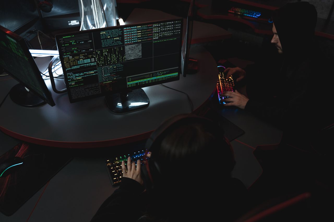 gallery-06 A group of people in a dark room working on computers, related to cybersecurity.